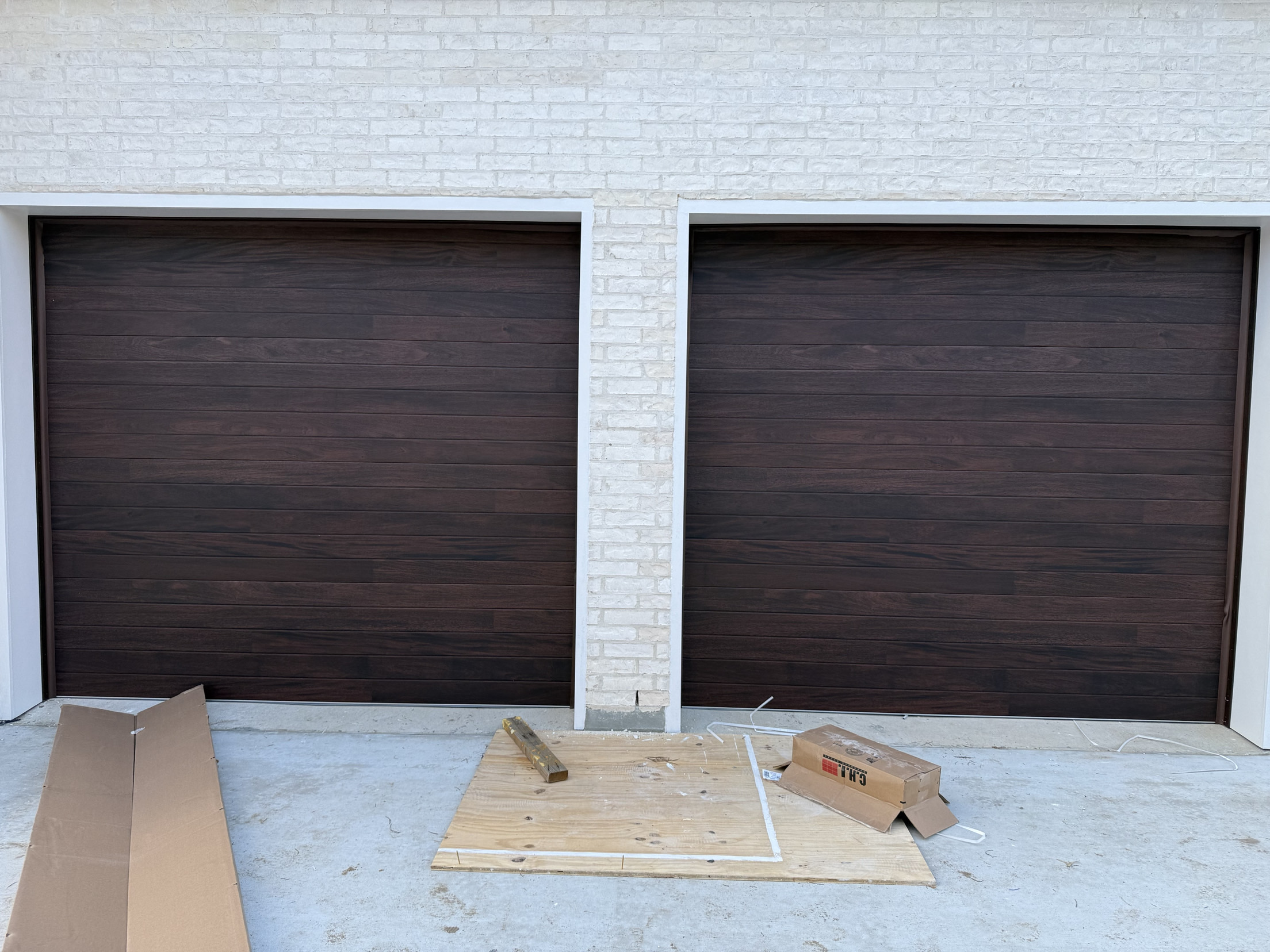 Modern dark walnut-finish garage doors on a new construction home